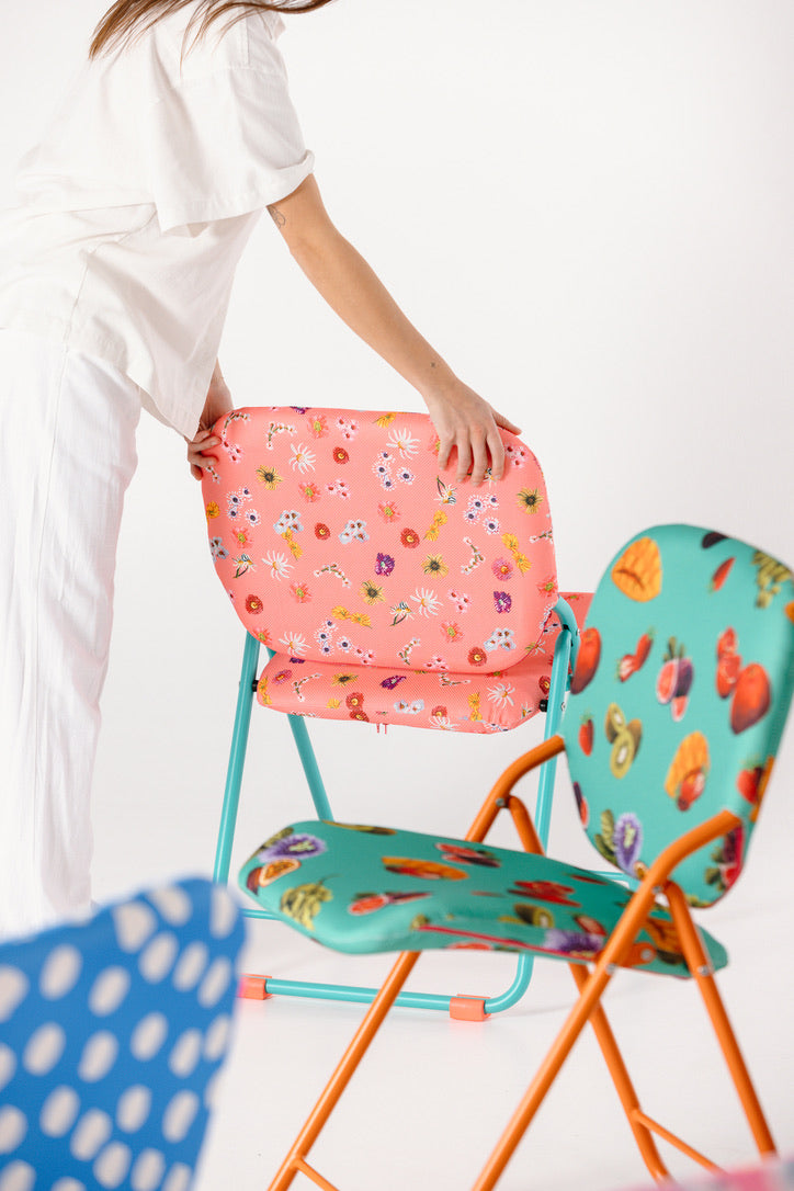 Two colorful folding chairs with floral and fruit patterns on a white background