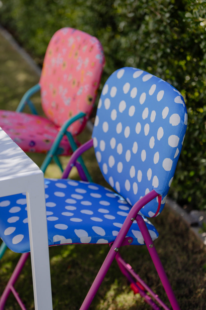 Colourful folding chairs with polka dot design on a grassy background