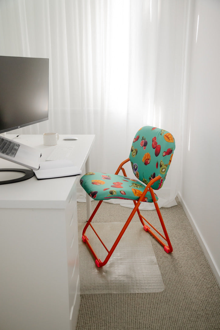 Colourful chair with next to a desk with a computer.