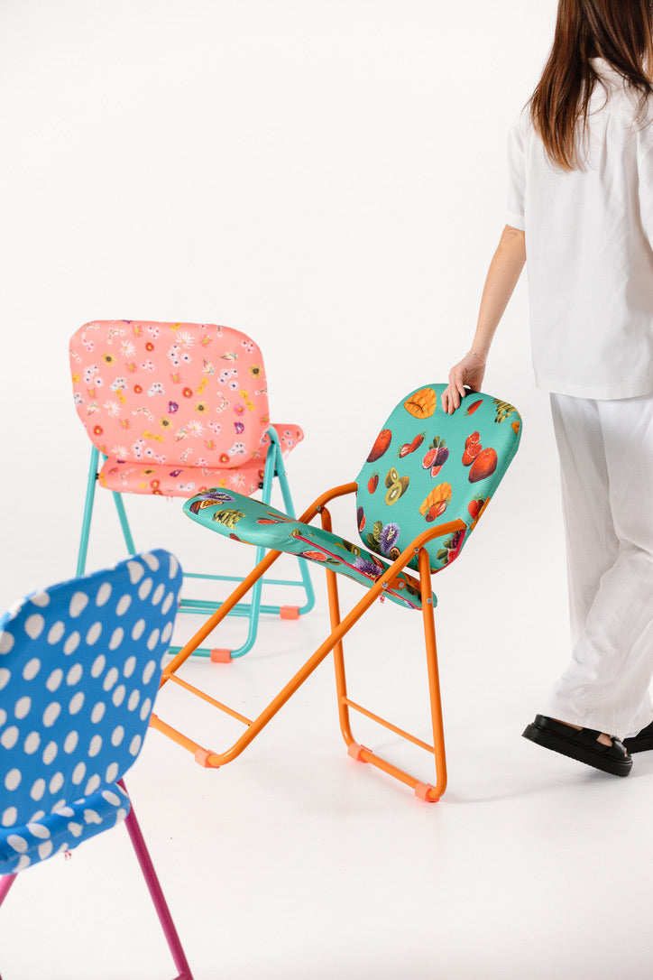 Colorful folding chairs with a person in a white shirt and pants on a white background